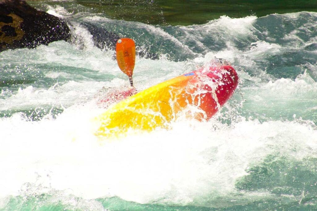 A whitewater kayak turning over violently