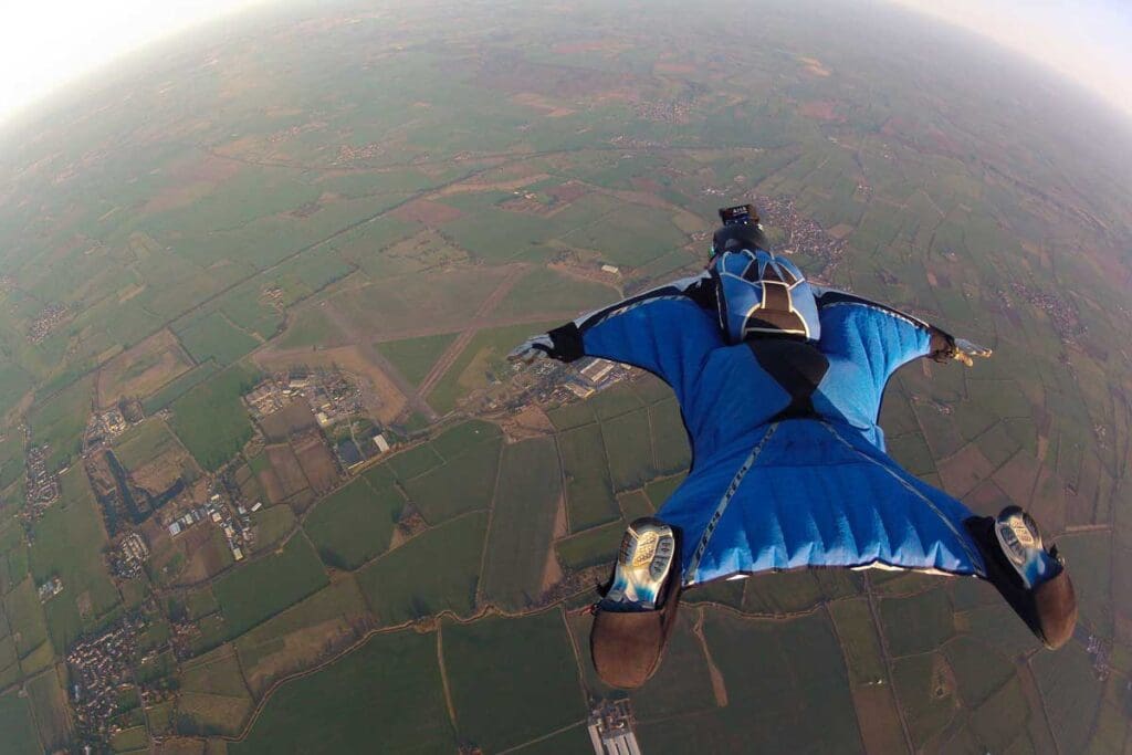 A man wingsuit flying from hundreds of feet in the air
