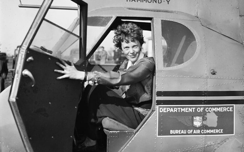 Amelia Earhardt sitting in an airplane cockpit with door open in 1936