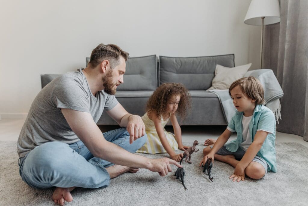 Dad and kids playing with toy dinosaurs