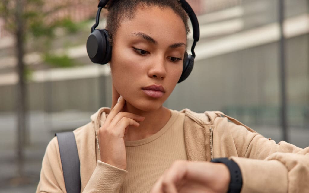 Woman with headphones on checks pulse with smartphone