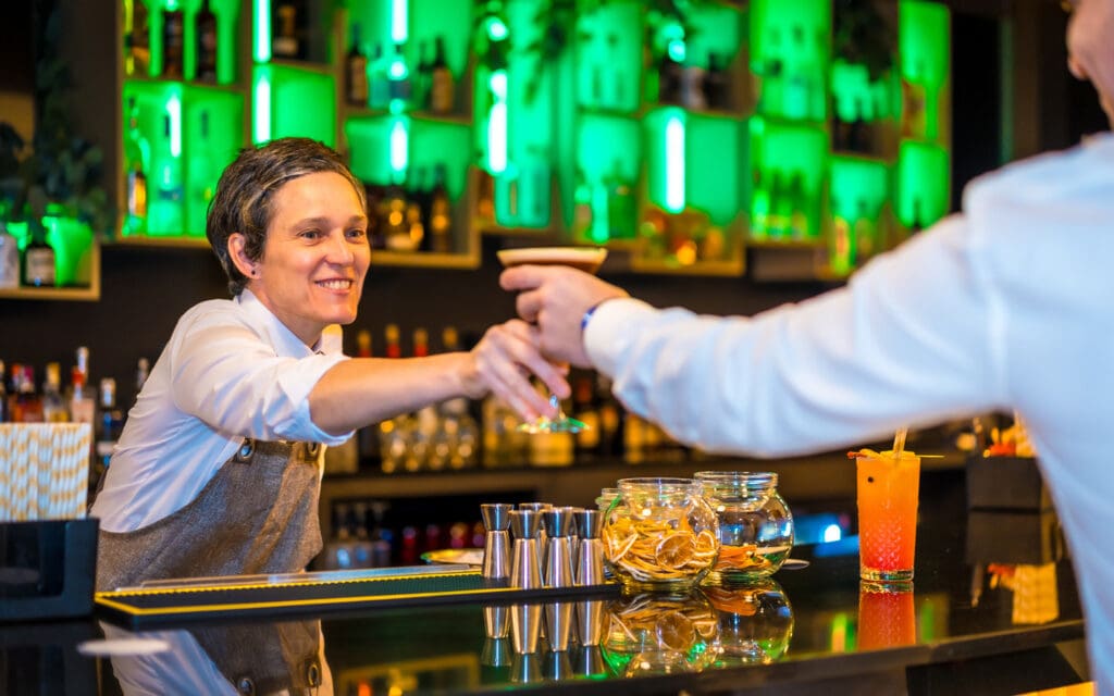 bartender handing cocktail to man