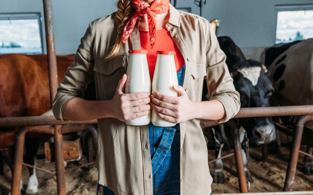 woman holding bottles of milk on a farm