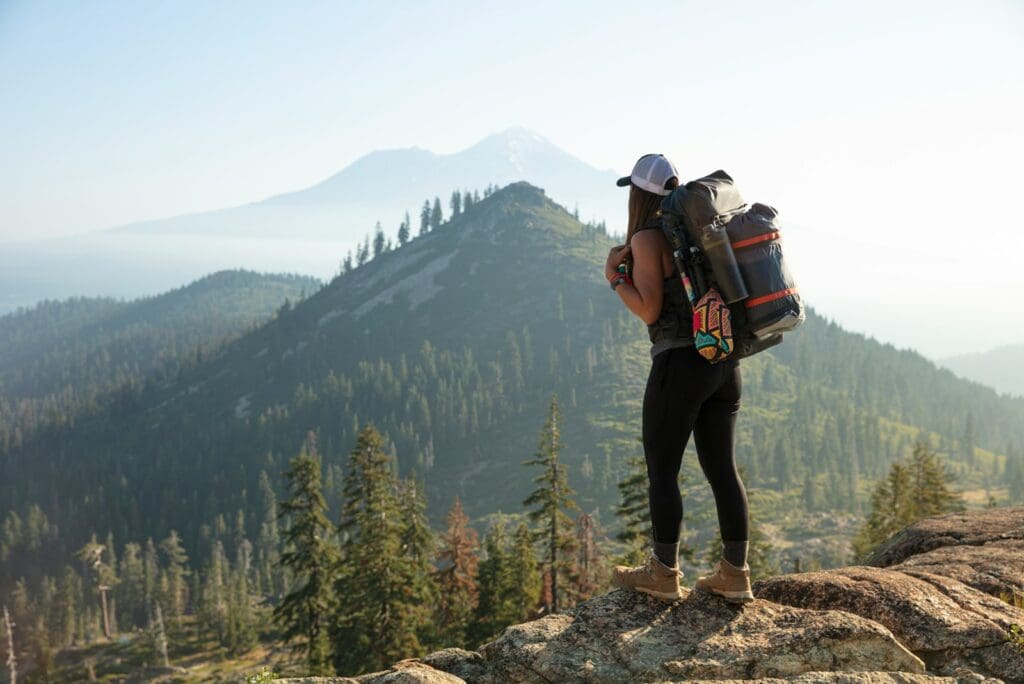 man in black jacket and black pants wearing black backpack standing on rocky mountain during daytime