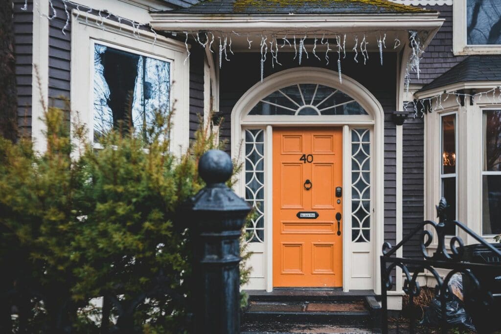 Exterior of contemporary wooden orange door and black cast iron gates to house