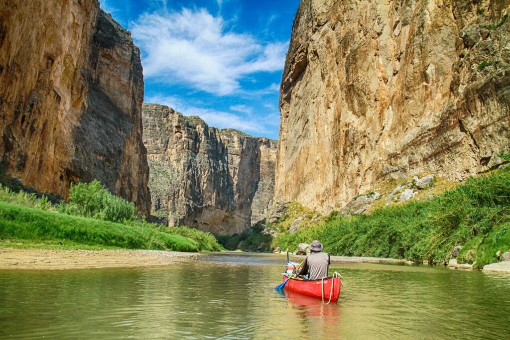 man in gray top sailing with red canoe boat during daytime