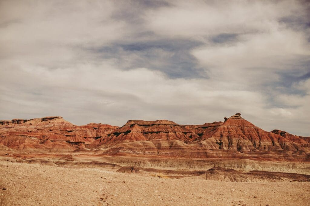 a desert landscape with mountains and clouds in the background