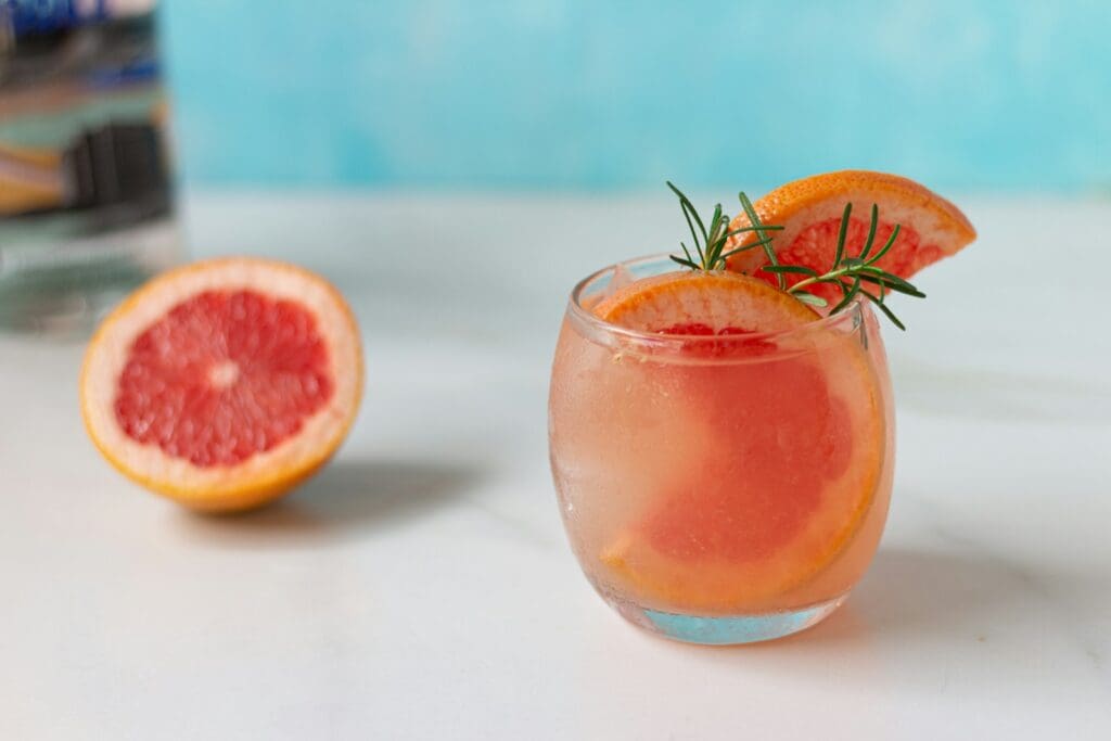 a grapefruit cocktail garnished with a rosemary garnish