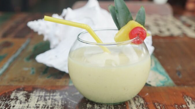 a glass filled with a drink sitting on top of a wooden table