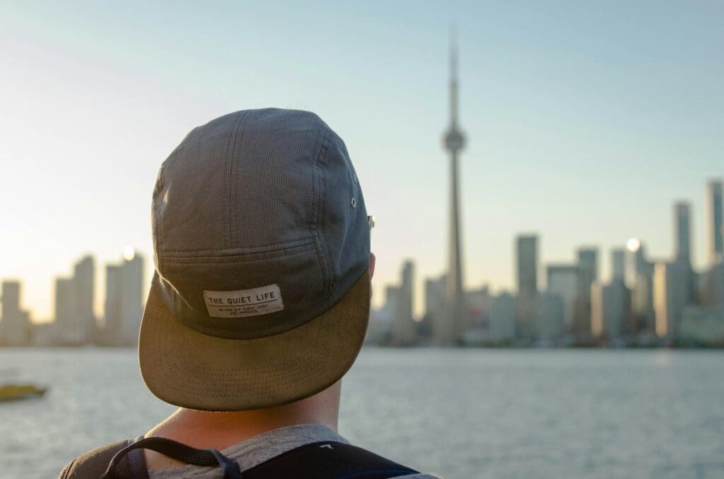 person wearing gray hat facing on city during daytime photography