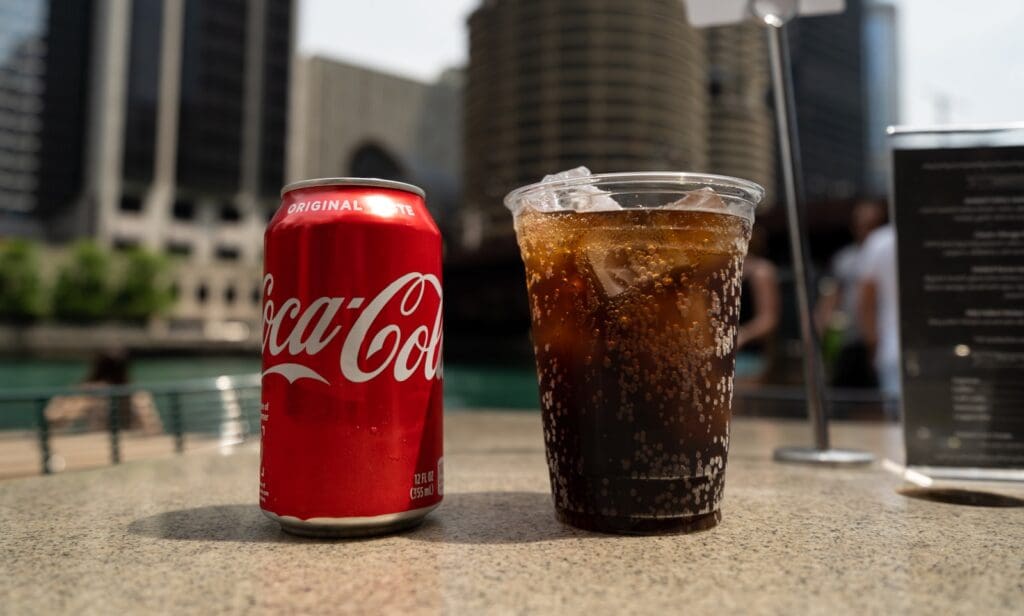 Coca-Cola soda tin can and cup on table close-up photography