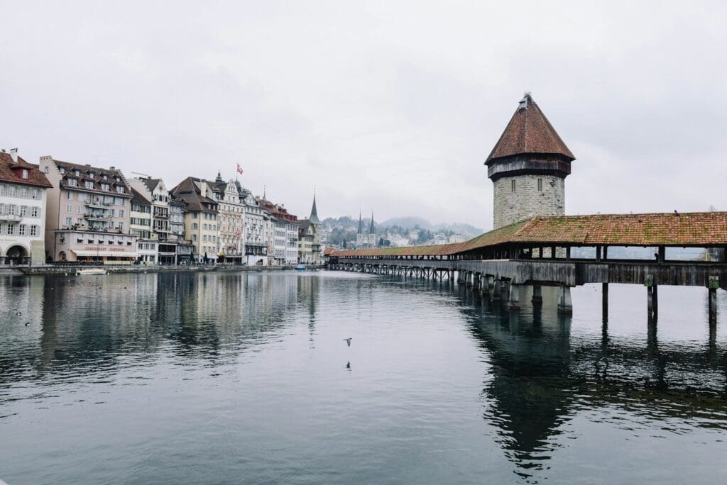 body of water near concrete buildings under white and gray sky at daytime