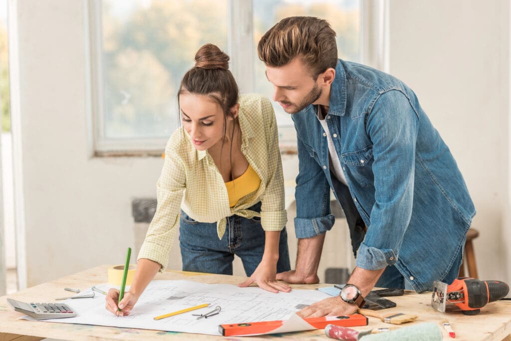 young couple marking blueprint and discussing renovation together