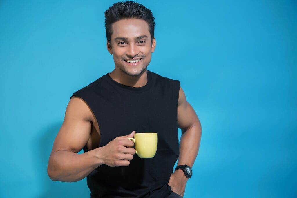 man in black tank top holding yellow ceramic mug