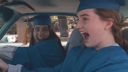 two girls in graduation caps and gowns driving a car