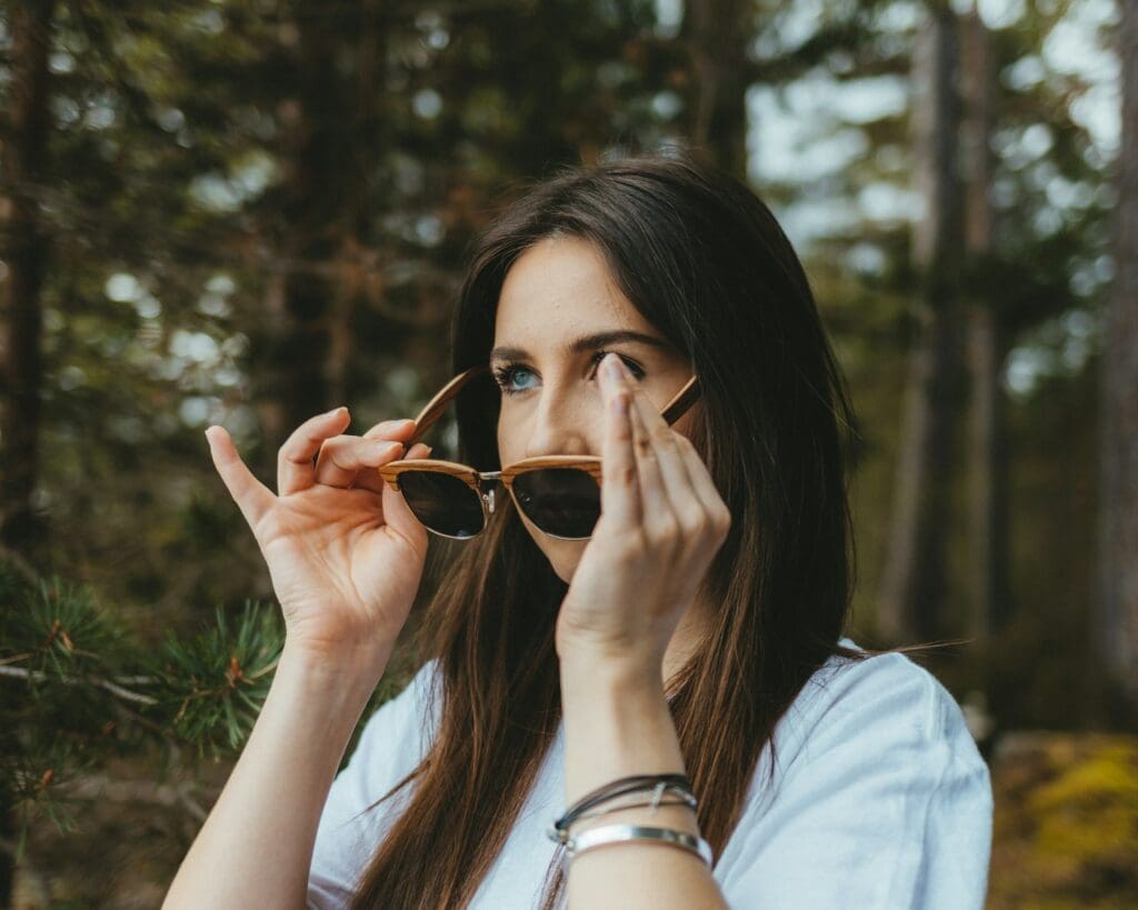 a woman holding her sunglasses up to her face