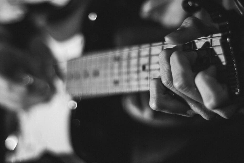 grayscale photo of person playing guitar