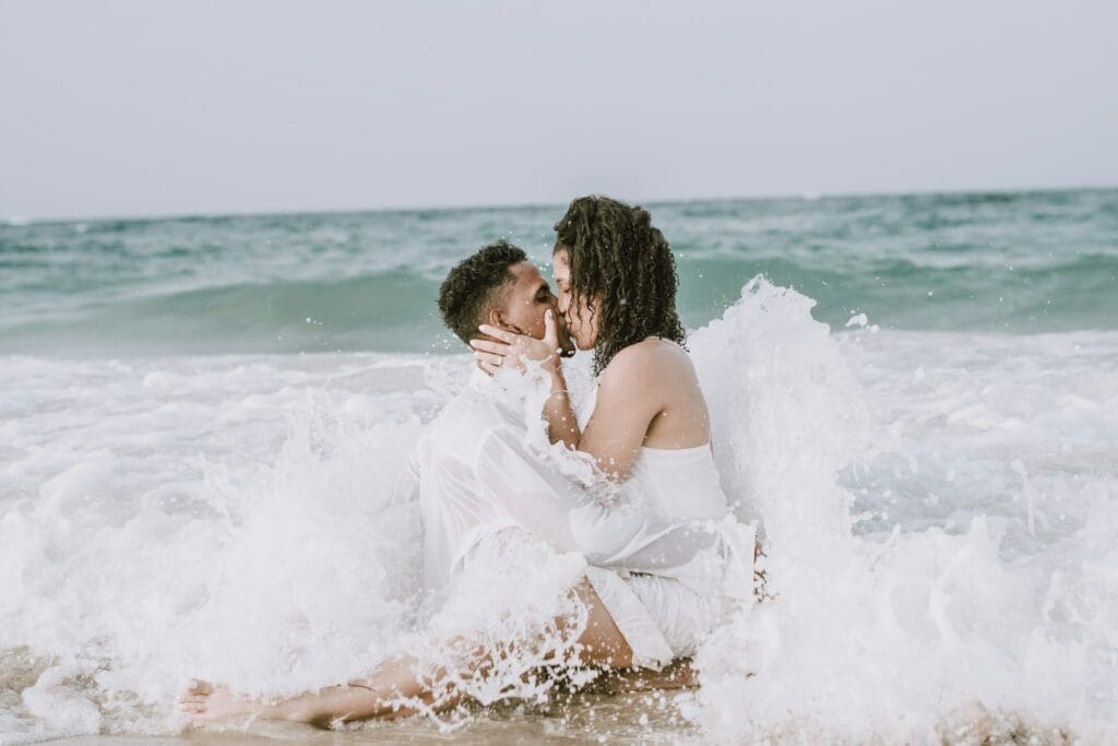 couple kissing on beach during daytime