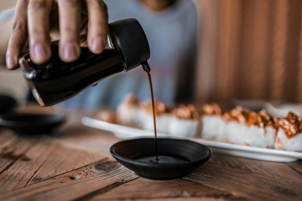 person pouring soy sauce