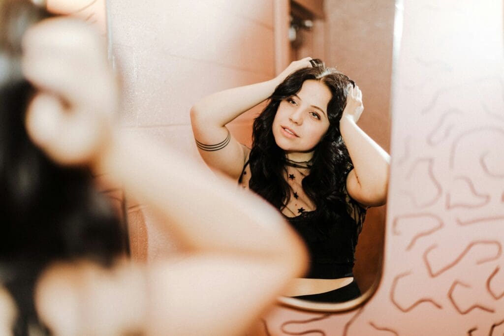 a woman standing in front of a mirror brushing her hair