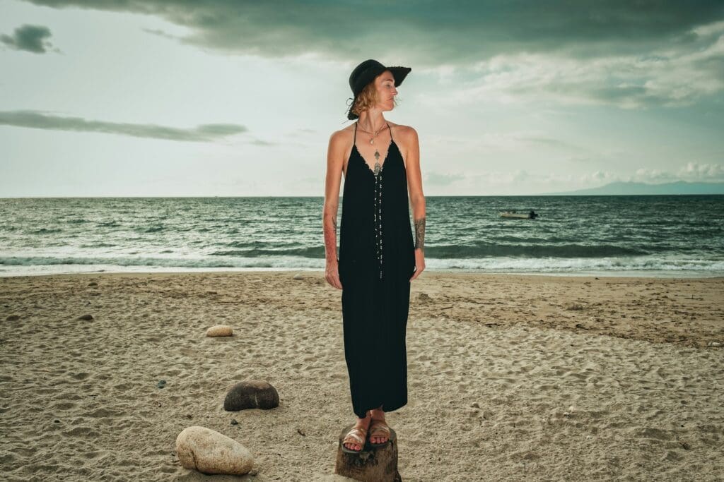 woman in black halter dress standing on beach during daytime