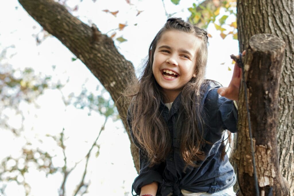 woman in black leather jacket standing beside brown tree during daytime