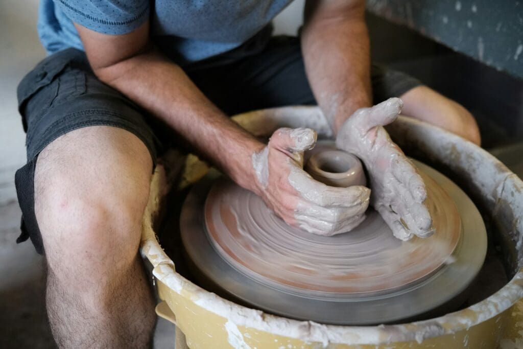 person making clay pot on the floor