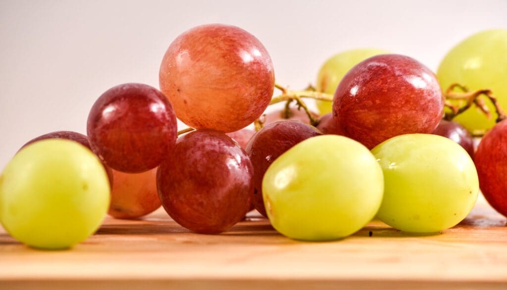 a bunch of grapes sitting on top of a wooden table