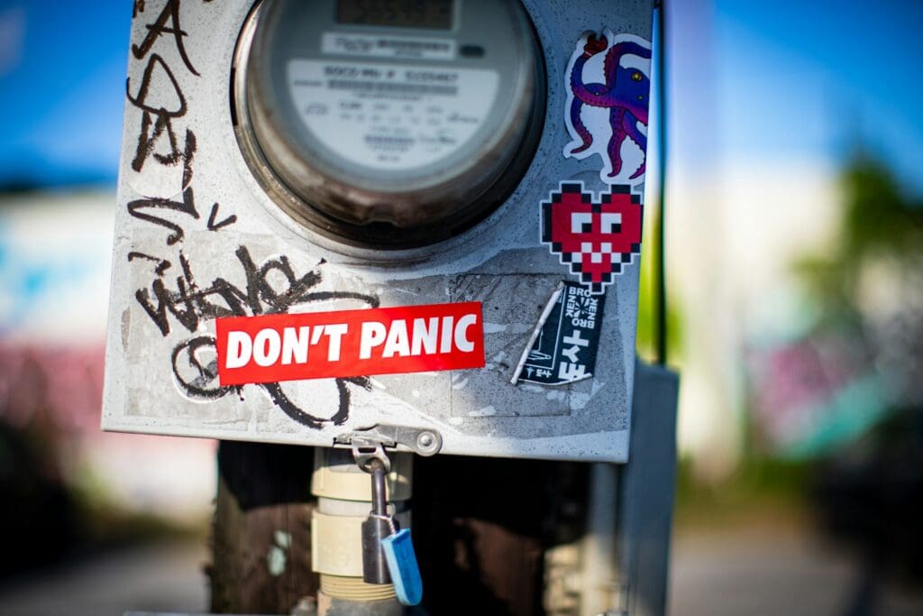 A parking meter with a don't panic sticker on it