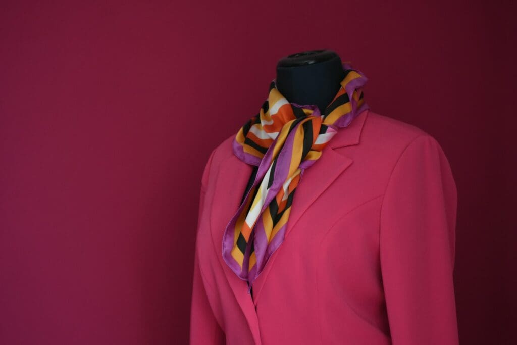 a mannequin wearing a pink coat and a multicolored scarf