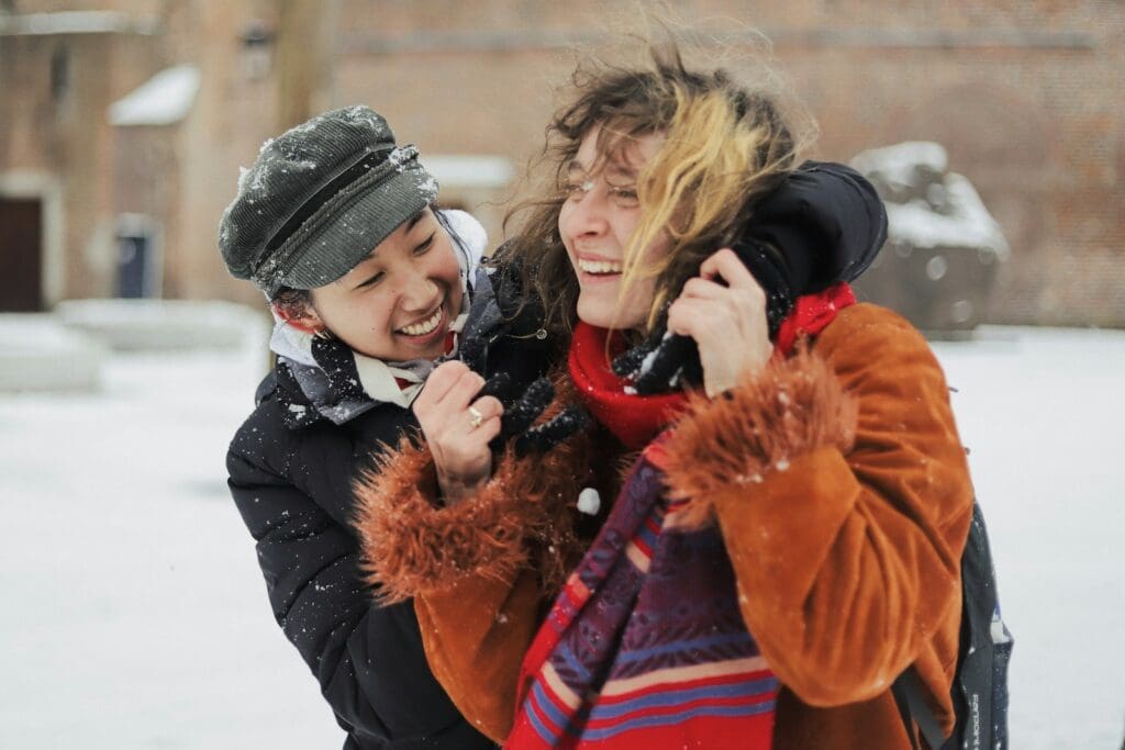 woman in black jacket carrying girl in orange jacket