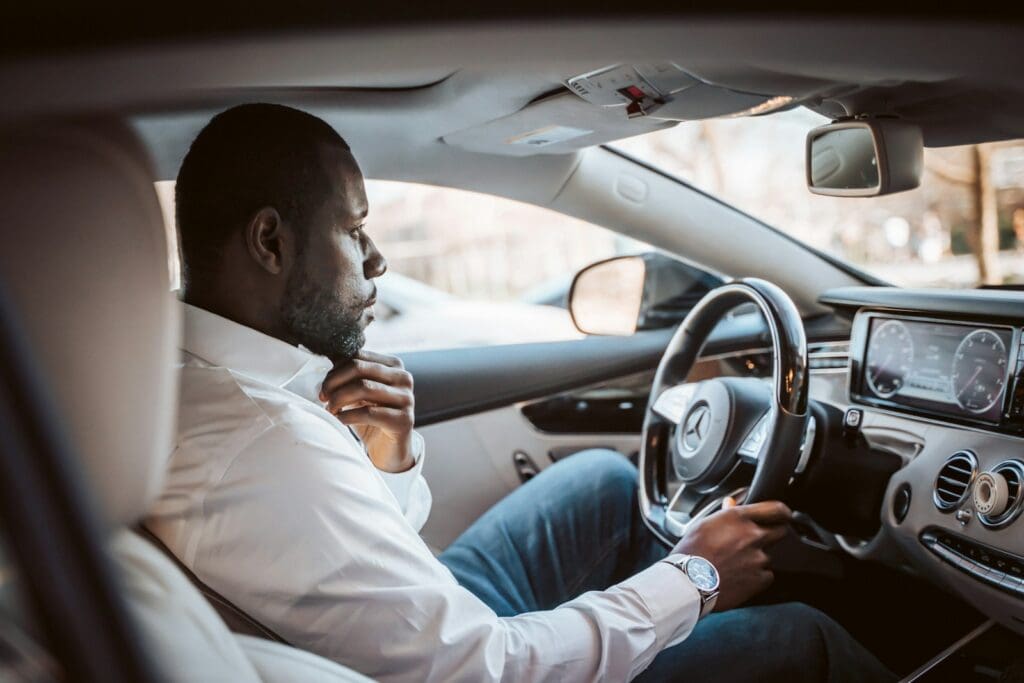 man in white dress shirt driving car during daytime