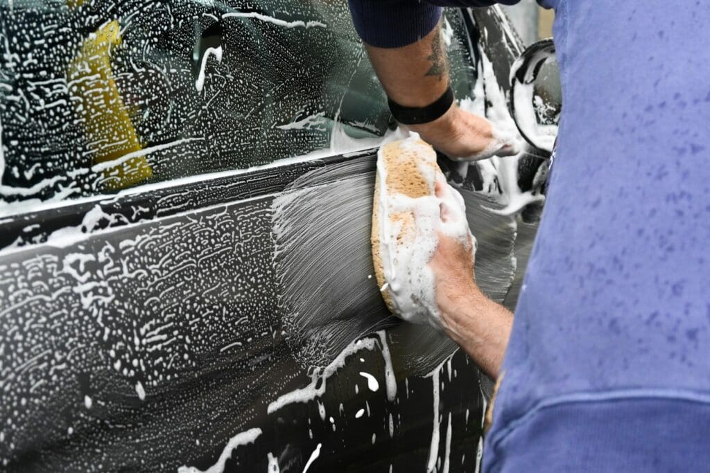 a man washing a car with a sponge