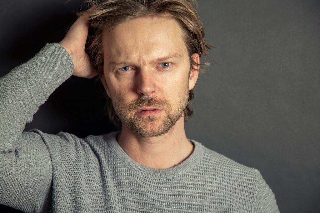 a man with a beard and blue eyes posing for a picture