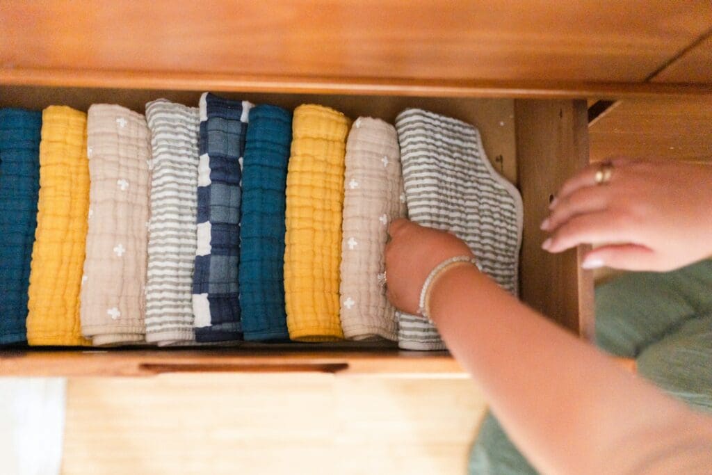 a woman is looking at a drawer full of baby blankets