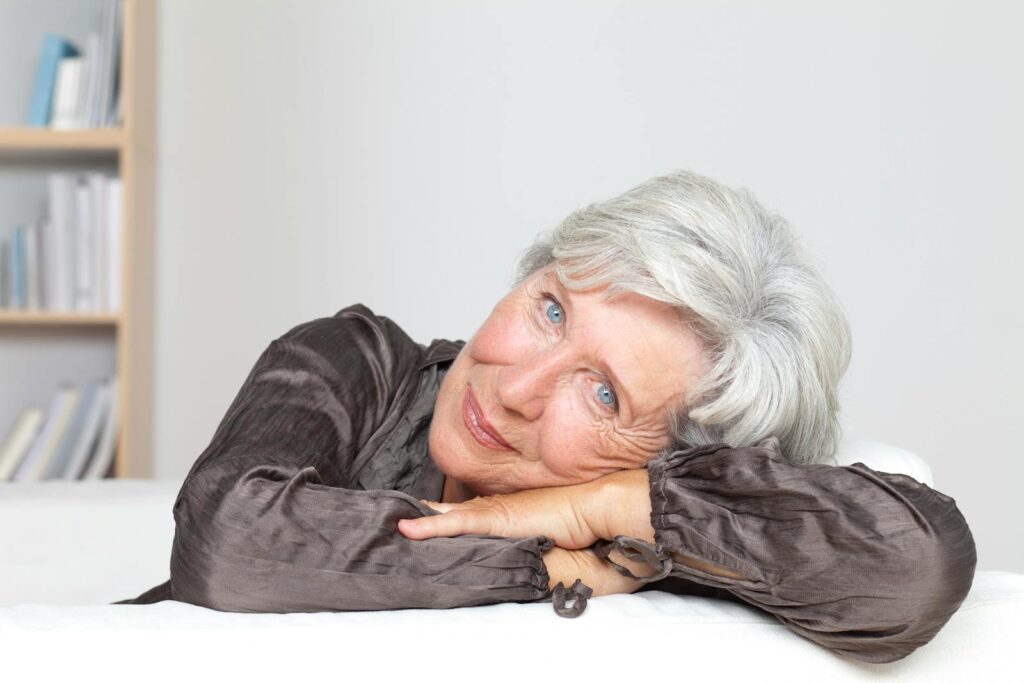 Smiling Woman with her Hands and Head on a Table