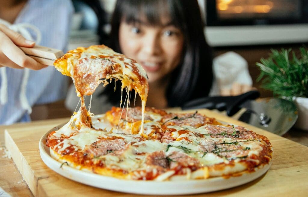 Women taking piece of pizza with tomatoes and cheese