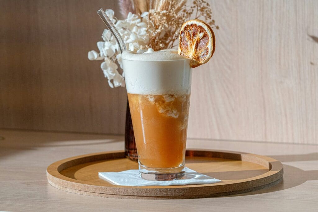 a drink on a tray with a flower arrangement in the background