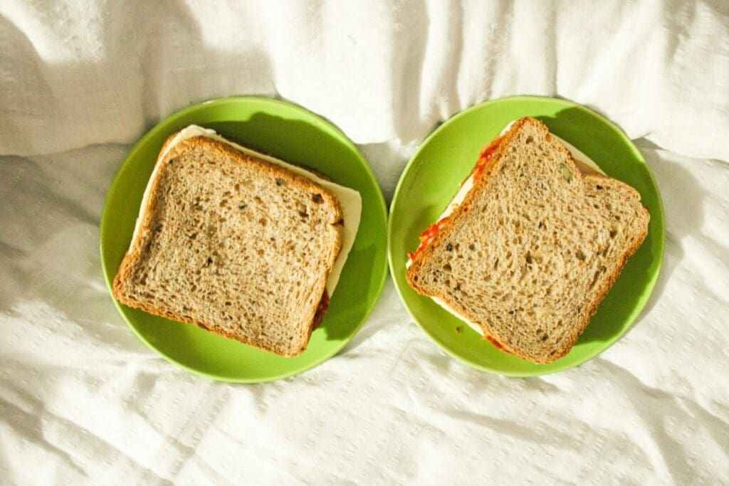 two green plates with sandwiches on them on a bed