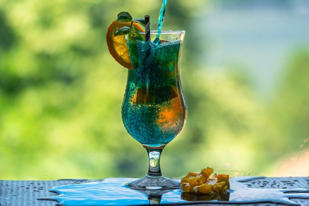 blue and orange wine glass with blue liquid and ice