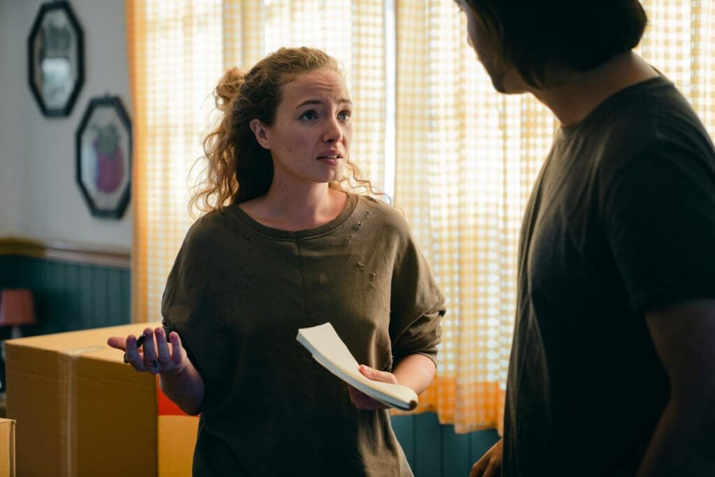 A couple engaged in a conversation while preparing to move in a warmly lit living room.