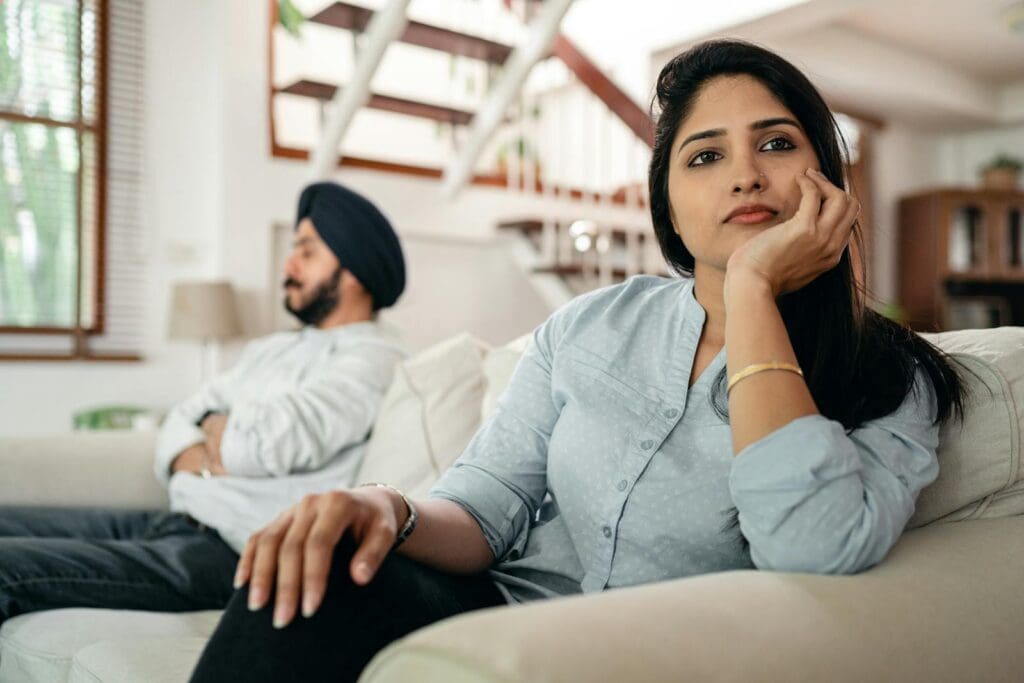 Young couple experiencing a conflict at home, showcasing emotional distance and contemplation.