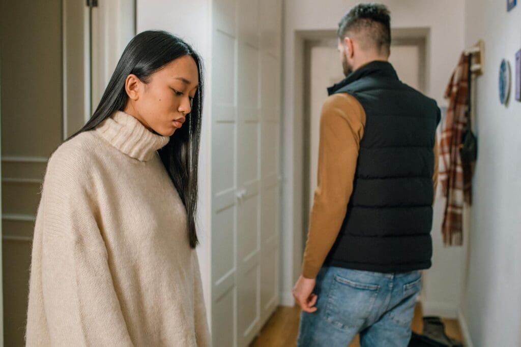 A Woman in Cream Sweater Behind a Person in Black Vest