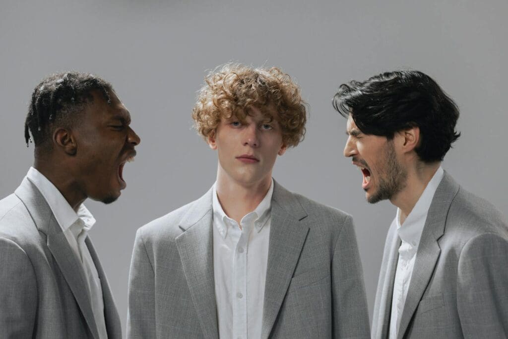 Three men in office attire expressing emotion in a corporate setting.