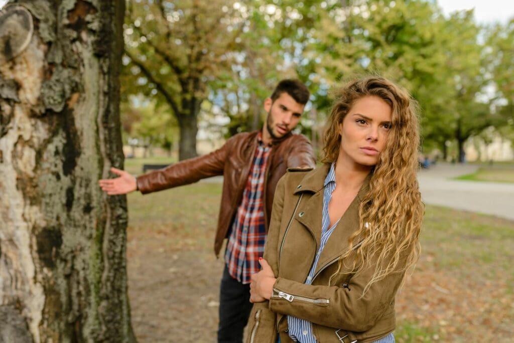 A man and woman in a heated argument outdoors, expressing emotions.