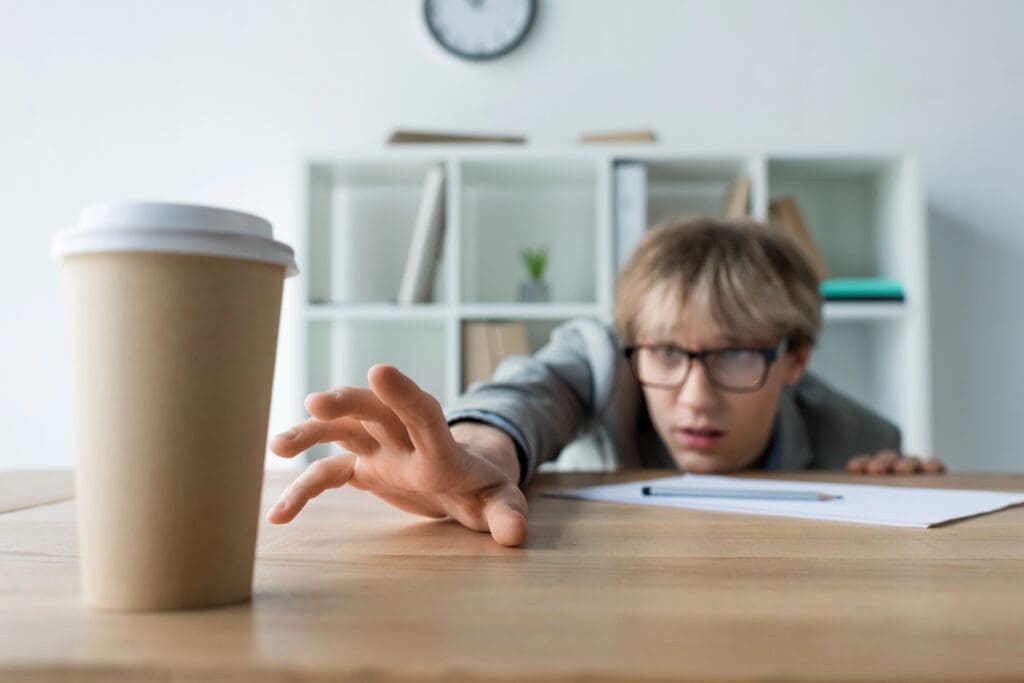 Businessman reaching for coffee in paper cup