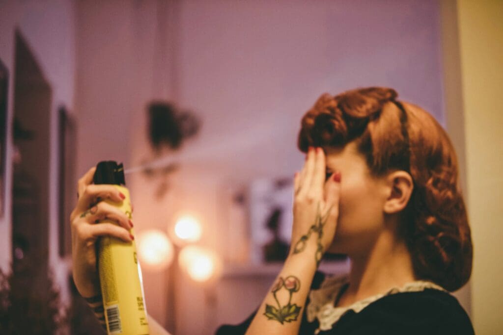 woman in black and white floral shirt holding yellow and black spray bottle