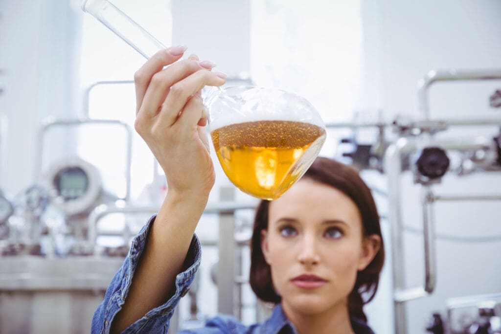 Stylish brunette in denim jacket looking at beaker of beer