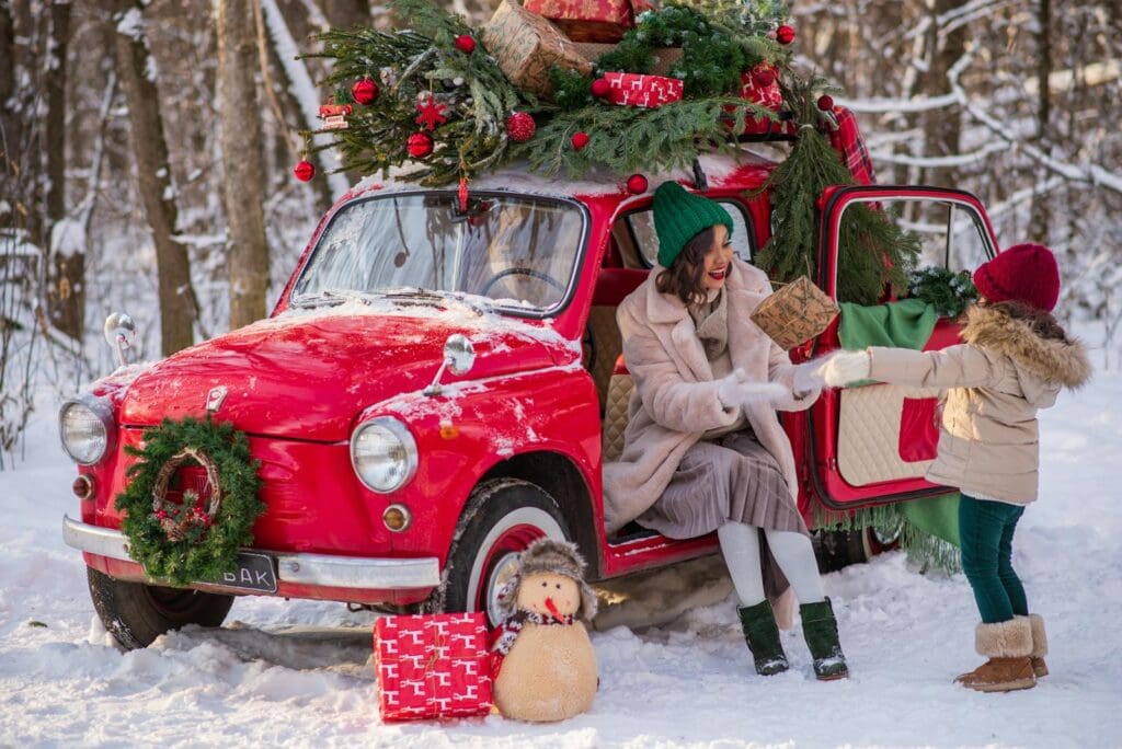 Mother and child enjoy winter with a decorated car and gifts in a snowy forest.