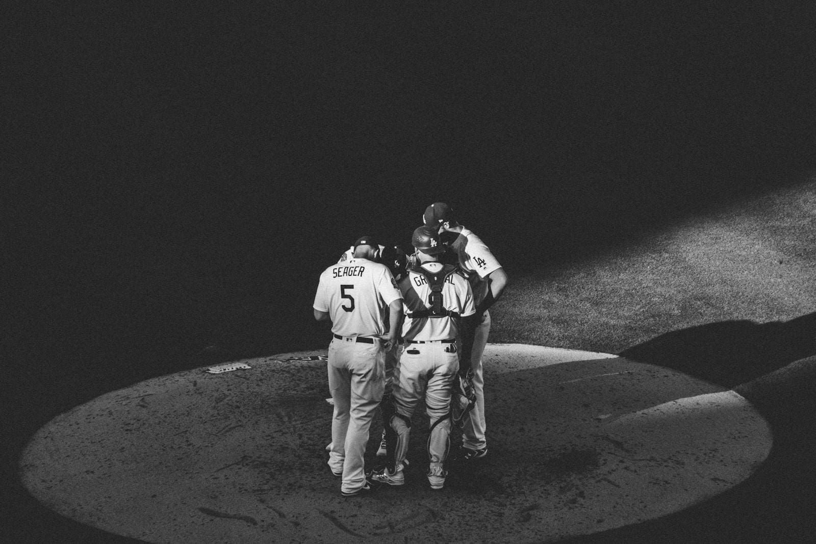 Black and white image of a baseball team huddling on a field under spotlight in Los Angeles, CA.